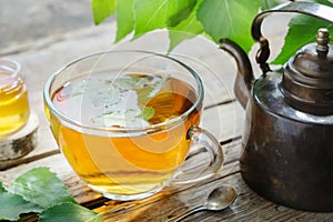 Birch leaves, healthy herbal tea cup, honey jar and vintage copper tea kettle