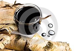 Birch tar or pitch in a jar and birch tree bark on white background. Wood tar