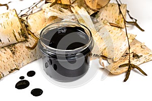 Birch tar or pitch in a jar and birch tree bark on white background. Wood tar