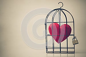 A bird cage with a red heart inside