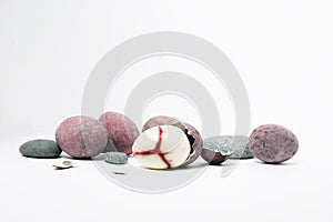 Bird eggs among stones, one broken with a red vein