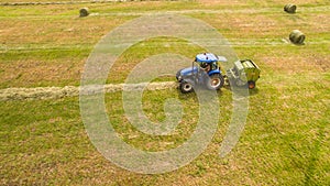 Bird eye of Man at work on the tractor with hay baler