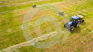 Bird eye of Man at work on the tractor with hay baler