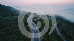 A bird eye scenery view of a winding road cutting turns through clouds of serpentine a dense forest , mountain landscape.Top Down