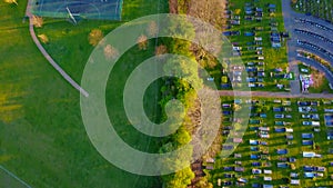 Bird eye view down a line of trees bisecting a cemetery and basketball court