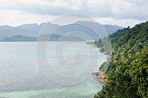 Bird eye view of tropical landscape with stone coastline, coconut palm trees, tropical sea and mountains on Koh Chang island