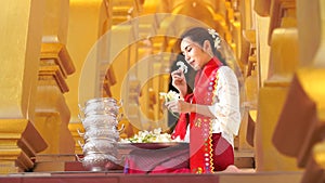 A bird flew over, a woman sitting with flowers. Young woman with traditional burmese holding flower on hand at beautiful golden pa