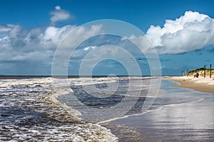 Bird flying over waves at beach with couple sitting on chairs by fence