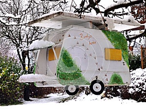 Bird house in special caravan design in snowy scenery