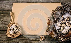 Bird nest with eggs from one side and coil of rope with quail eggs in other side of sheet of paper for text on rustic wood backgro