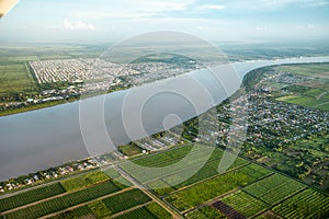 Bird`s-eye view of the Demerara River, rural houses, rectangular green fields taken from an airplane, South America. Rivers