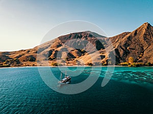 Bird`s Eye View of an Dive Boat in front of Komodo Island with visible Reef, Indonesia. Liveaboard Drone Shot.