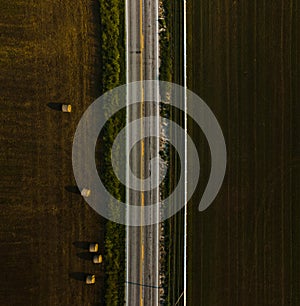 A bird's-eye view of an empty road, which is located next to the field.