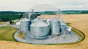 A bird's-eye view of modern granaries in the middle of a ripe golden wheat field. Bunkers for grain in the middle of