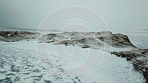 A bird\'s-eye view of the mountain range, half covered with snow, on the shore of the lake