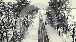 Bird's eye view of a narrow country road in winter, snow all around.