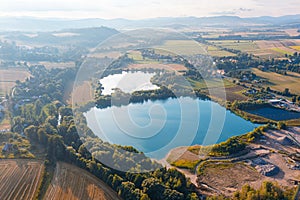 Bird`s eye view panorama of a blue lake with fields, trees and houses