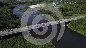 A bird's-eye view of summer. Clip. The bridge on which cars drive over the river, next to which there is a forest