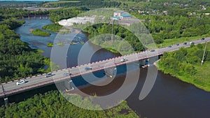 A bird's-eye view of summer. Clip. The bridge on which cars drive over the river, next to which there is a forest behind