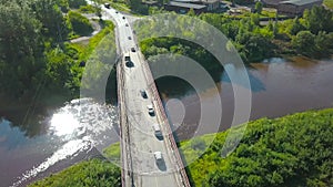 A bird's-eye view of summer. Clip. The bridge on which cars drive over the river, next to which there is a forest behind
