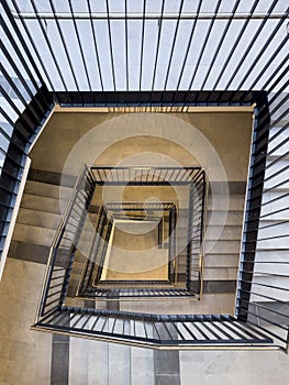 Bird's-eye view from top to bottom of stairwell in tall block of flats with banisters