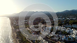 Bird's-eye view of an urban landscape meeting the azure sea, under the warm glow of sunset. Costa Del Sol, Marbella