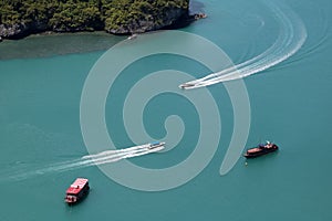 A bird\'s-eye view of various tour boats sailing in the sea, the white waves look beautiful