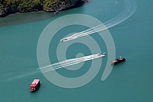 A bird\'s-eye view of various tour boats sailing in the sea, the white waves look beautiful