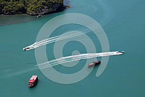 A bird\'s-eye view of various tour boats sailing in the sea, the white waves look beautiful