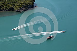 A bird\'s-eye view of various tour boats sailing in the sea, the white waves look beautiful