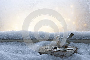 Bird toy standing on window sill covered with snow. Winter and Christmas outdoor decoration. Close up, Copy space,