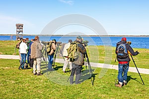 Bird watchers with binoculars by a lake