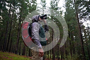 Bird watching, woods and man with binocular, travel and hiking with trees and adventure with hobby. Person, forest and