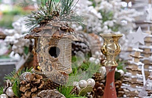 Birdhouse with gold sequins in a Christmas composition with cones and a candlestick.