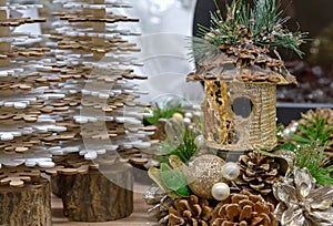 Birdhouse with gold sequins in a Christmas composition with cones and pearls.