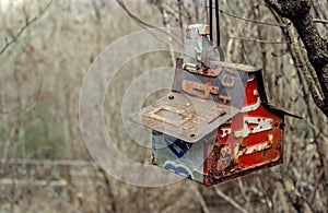 Birdhouse made with various old license plates hanging from a tree