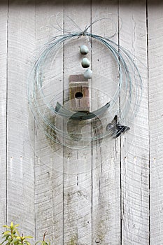 Birdhouse and wire wreath on wall