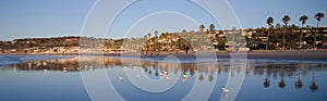 Birds, beachgoers and reflections at low tide during sunset at L