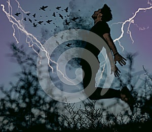 Birds burst out of the chest of a young man at a stormy night with flashes of lightning on the background