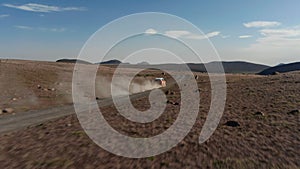 Birds eye flying above the car driving offroad through rural countryside in Iceland. Aerial view car driving off road on