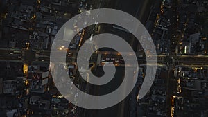 Birds eye shot of vehicles passing through road intersection on riverbank. Ascending footage of traffic in evening city