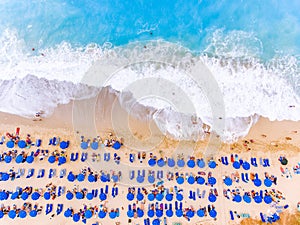 Birds eye view of a beach with big waves, sunbeds and umbrellas