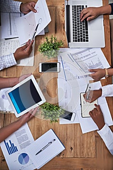 Birds-eye view of business. High angle shot of an unidentifiable group of businesspeople working together around a table