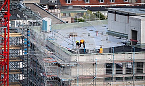 Birdseye view of roofer waterproofing the flat roof of a commercial building.