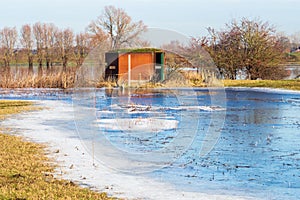 Birdwatching hide in dutch frozen Rammelwaard landscape