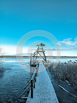 Birdwatching tower at the lakeside. Wooden pier that leads to a viewpoint.