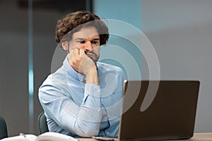 Bired business man leaning head on hand using pc