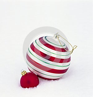 Birght, shiny red and green glass Christmas ornaments baubles decorations on white snow background