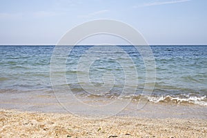 Birose blue sea, golden coast of small shells and sand, a clear horizon line and a clear sky. Soft sunlight, clear sky with