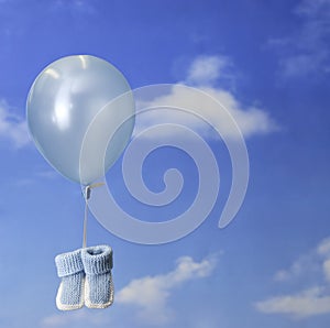 Birth concept:balloon carrying blue baby booties
